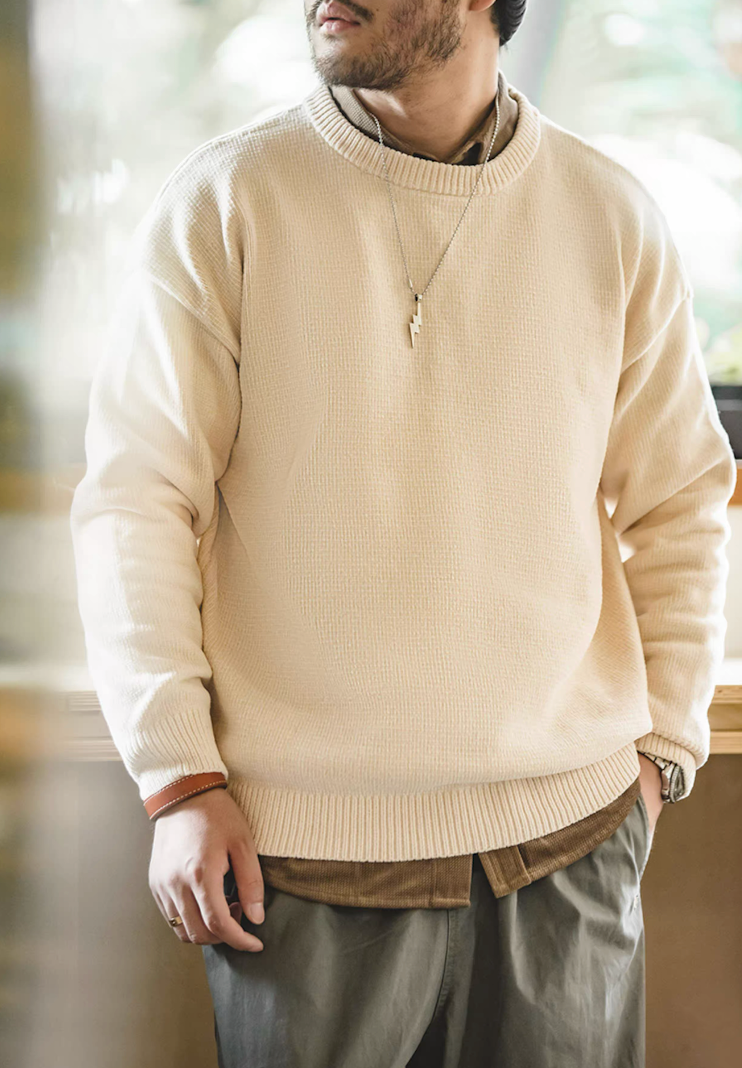 Model standing wearing cream chenille sweater in warm indoor light