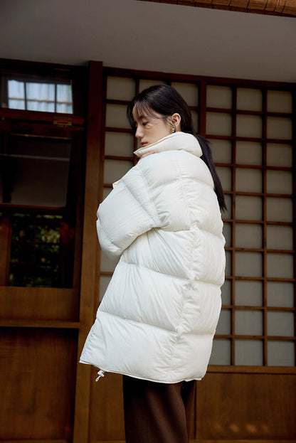Side-back view of off white Cloud-Contour Down Coat showing curved silhouette in front of shoji doors
