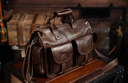 Side angle of dark brown leather weekender bag on wooden surface showing craftsmanship details