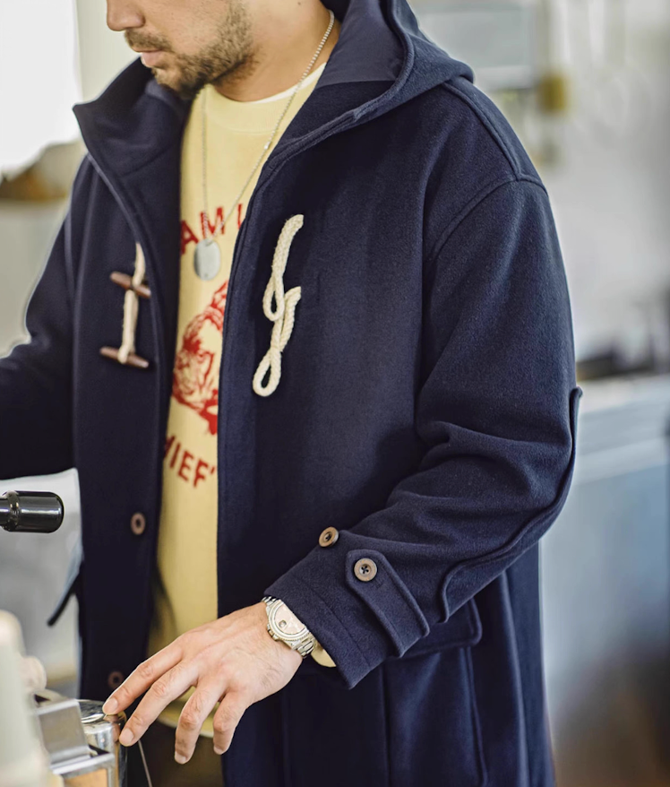 Model wearing navy toggle duffle coat with yellow graphic sweater