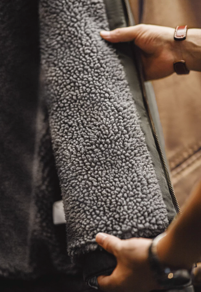 Close-up of soft grey sherpa lining inside dark green canvas jacket