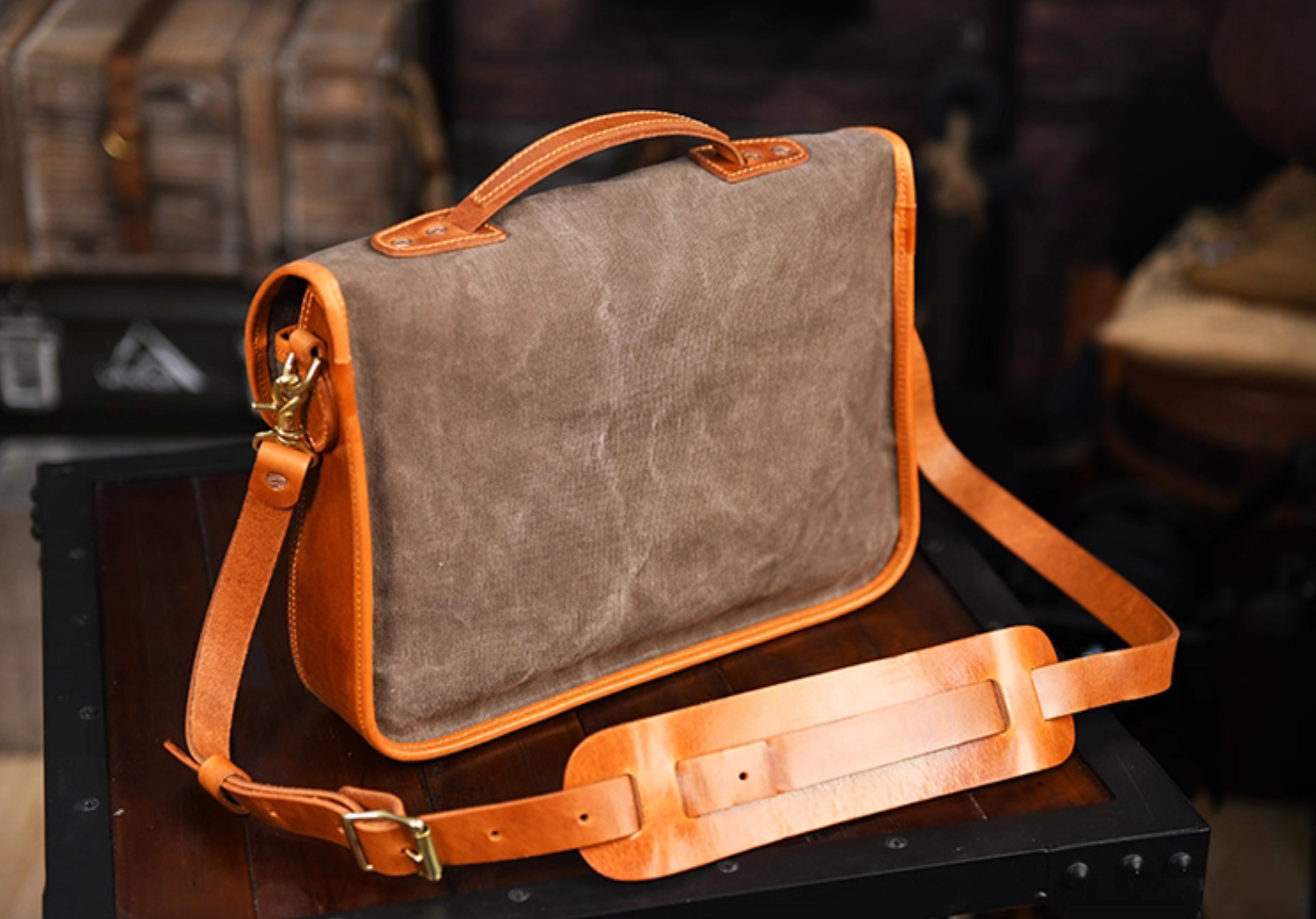 Rear view of khaki grey waxed canvas satchel with tan leather handle and shoulder strap