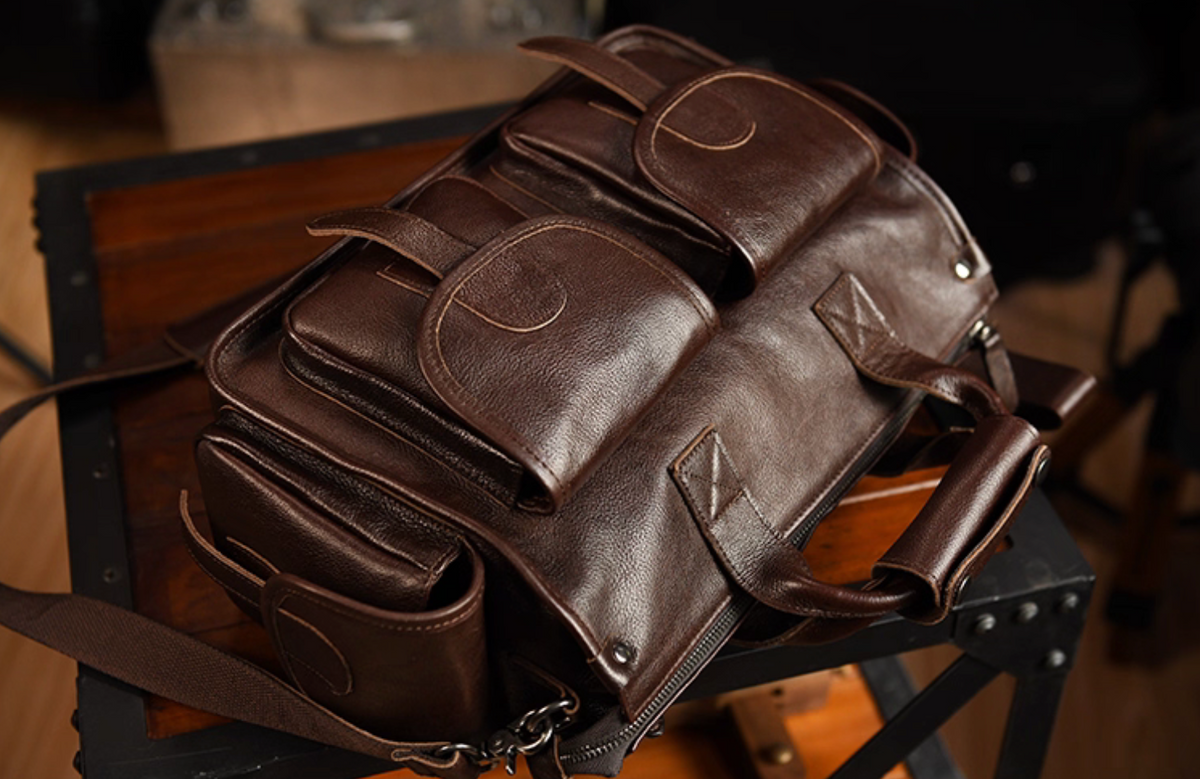 Top angle view of dark brown leather travel work bag showing multi-pocket design and textured grain