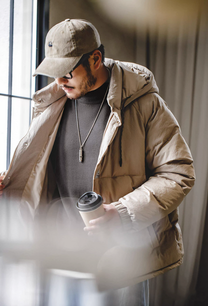 Men’s charcoal gray half turtleneck sweater layered under beige puffer jacket — cozy, minimalist winter outfit with warm neutral tones.