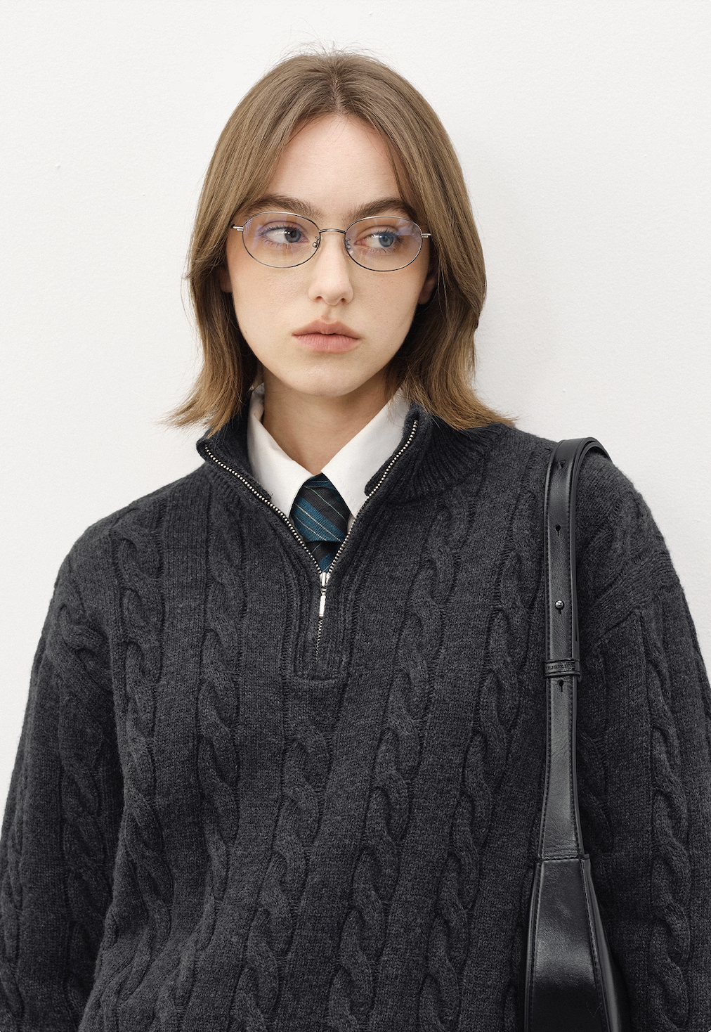 Close-up of unisex dark grey half-zip cable knit sweater with mock neck, paired with shirt and tie