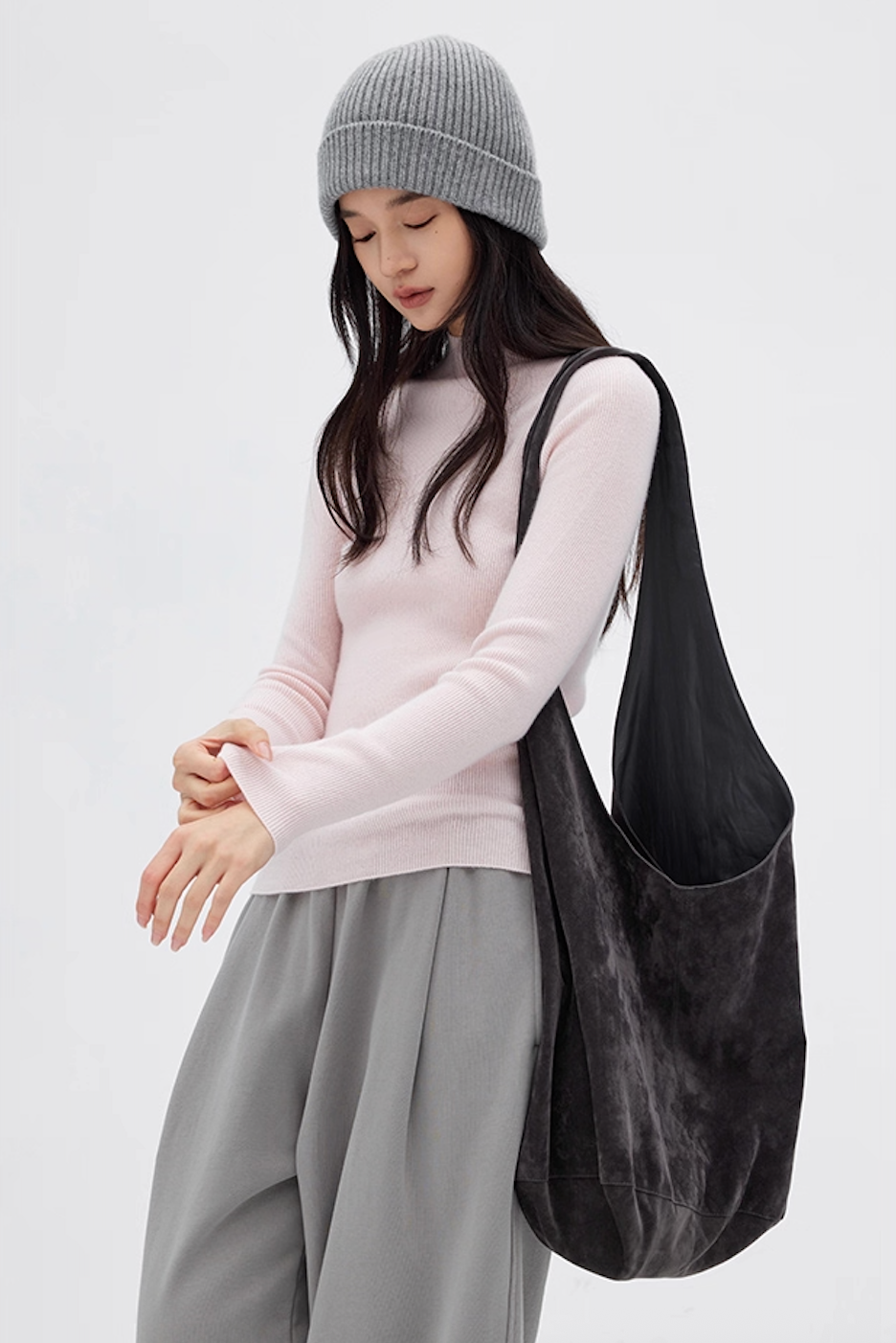 Woman in pale pink cashmere sweater paired with gray pants and soft tote bag, cozy casual style