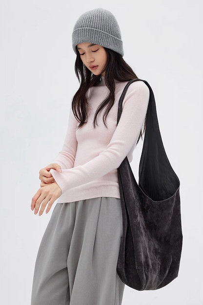 Woman in pale pink cashmere sweater paired with gray pants and soft tote bag, cozy casual style