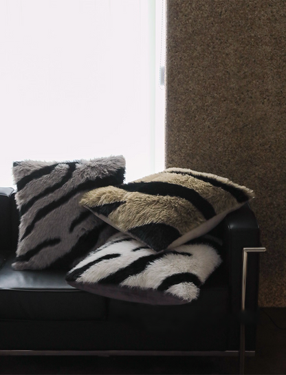Set of zebra stripe faux fur throw pillows in black white and camel colors on modern black sofa