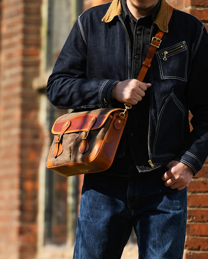 Man wearing khaki grey leather-trim messenger bag crossbody in city sunlight