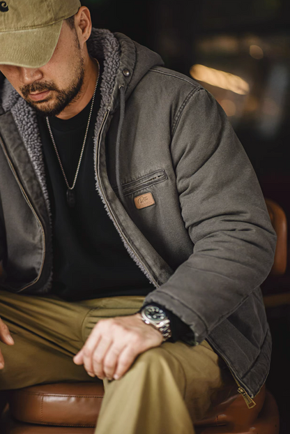 Dark green canvas jacket with grey sherpa lining worn open while seated, vintage washed finish visible