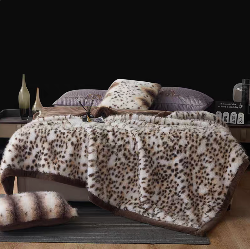 Snow Leopard White long-pile faux fur luxe throw blanket spread across bed with bold spotted pattern