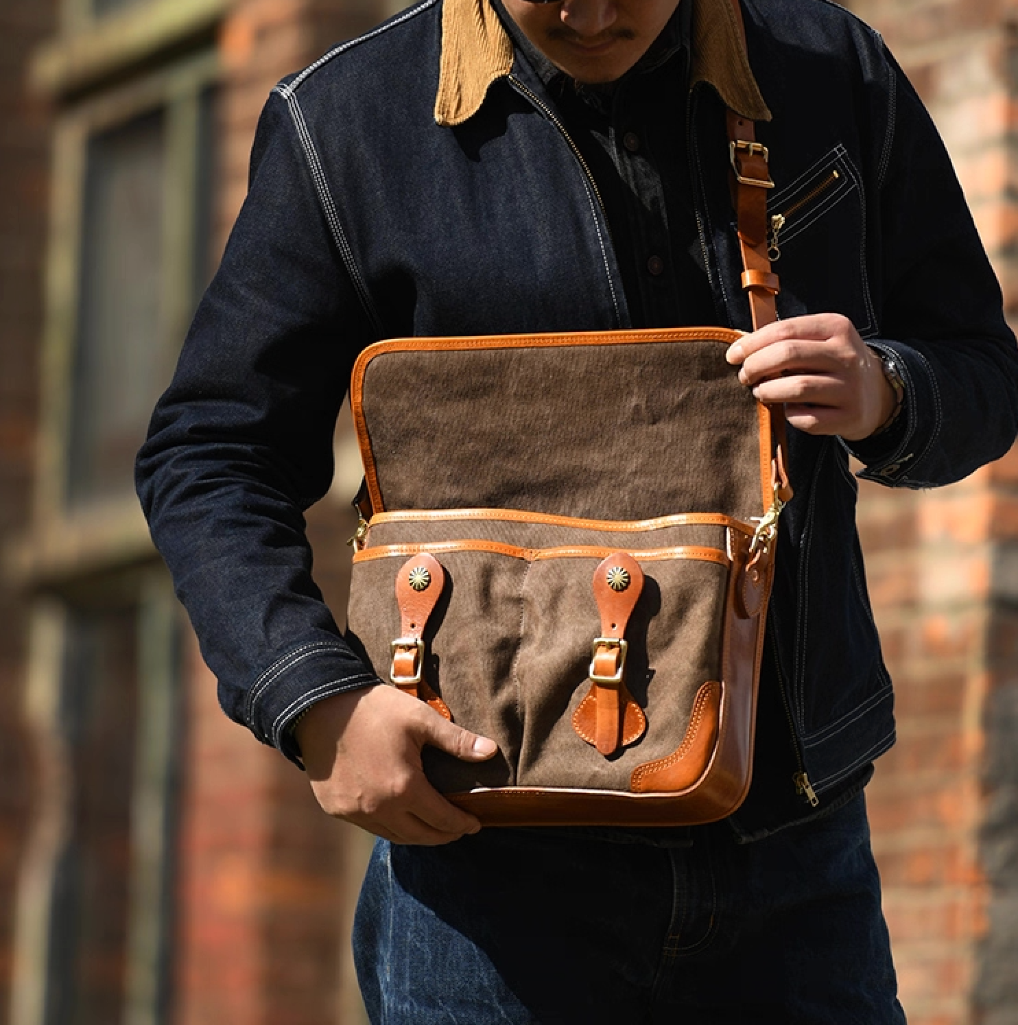 Person opening khaki grey canvas satchel revealing dual front pockets and interior