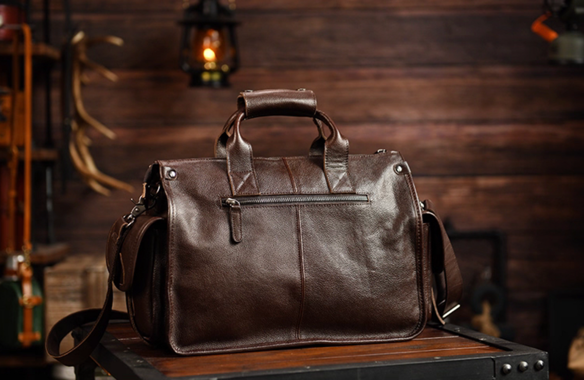 Rear view of dark brown leather travel bag with zip pocket and sturdy top handles