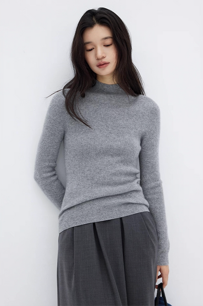 Model in heather gray cashmere sweater and pleated gray skirt, timeless luxury knitwear