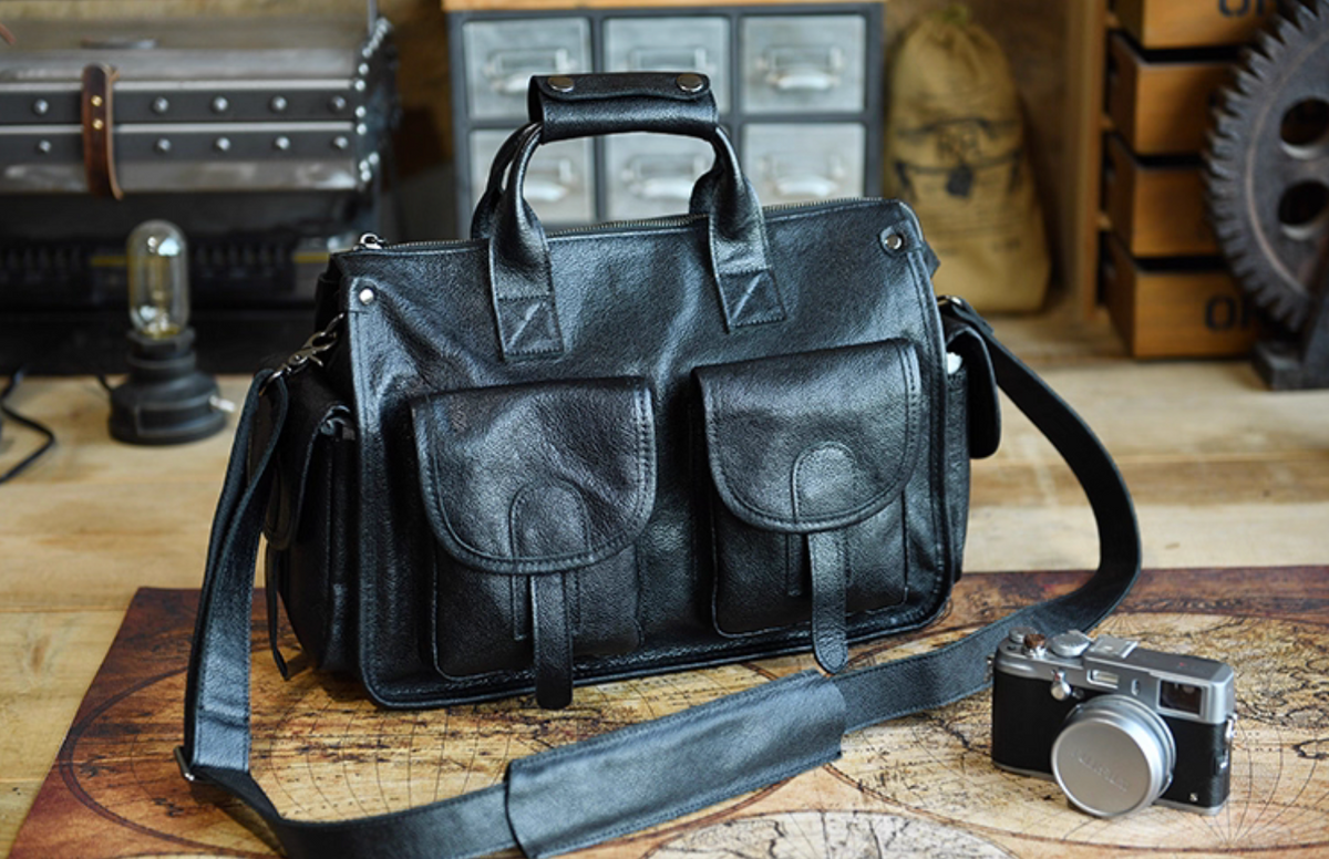 Front view of black full-grain leather weekender bag with twin front flap pockets and long strap