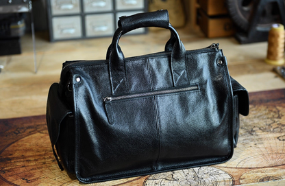 Back view of black leather duffle with zipper pocket and reinforced handle stitching