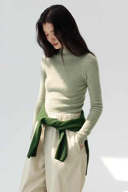 Relaxed look featuring moss green cashmere sweater, beige pants, and layered green knit tied at waist