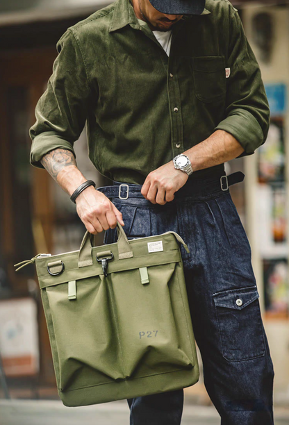 Model carrying army green canvas tote bag by hand outdoors, showing full bag size and structured shape.