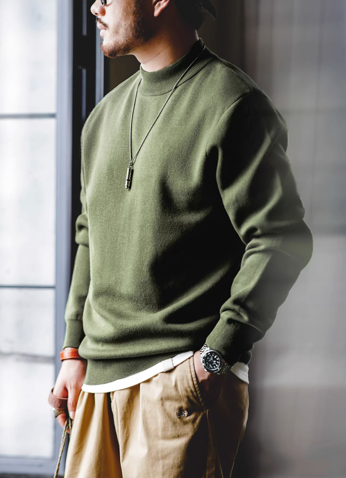 Man wearing army green knit pullover by window in casual style