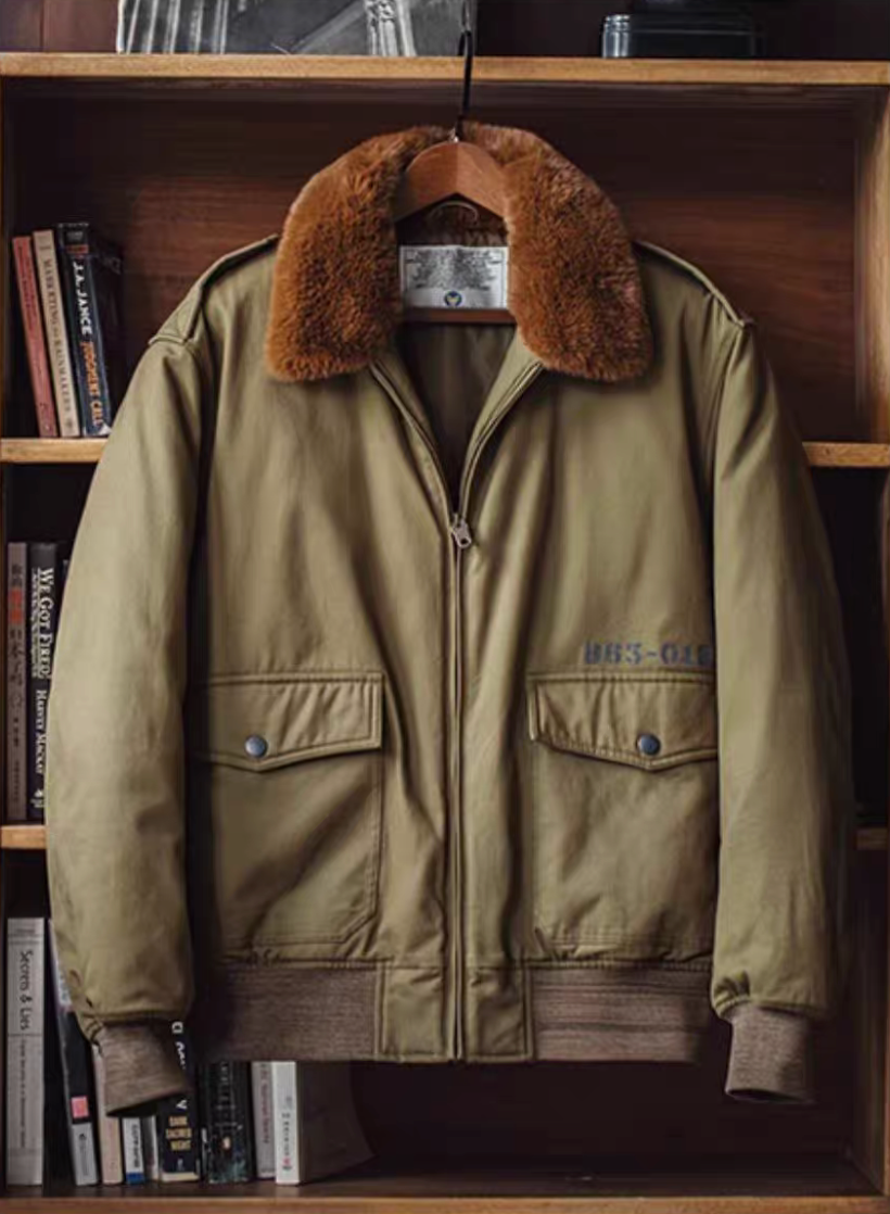 B-10 olive cotton bomber hanging on wooden hanger inside bookshelf, showing fur collar and label.