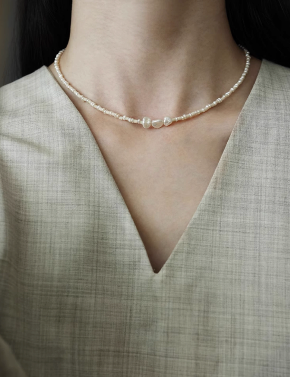 Model wearing baroque pearl and stone necklace with natural freshwater pearls and delicate beaded design in a minimalist front view