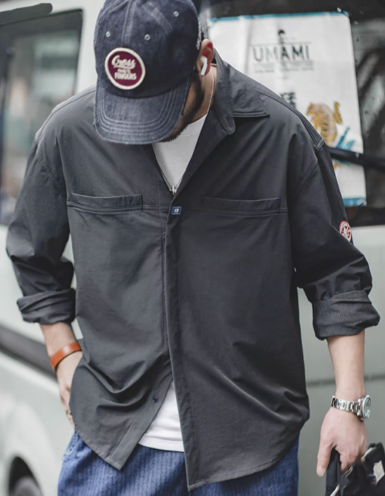 Model wearing men’s dark charcoal overshirt jacket styled casually with a cap.