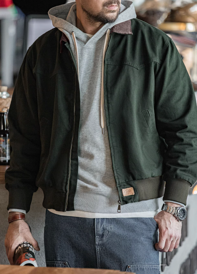 Man wearing dark green Santafe canvas bomber jacket layered over a gray hoodie.