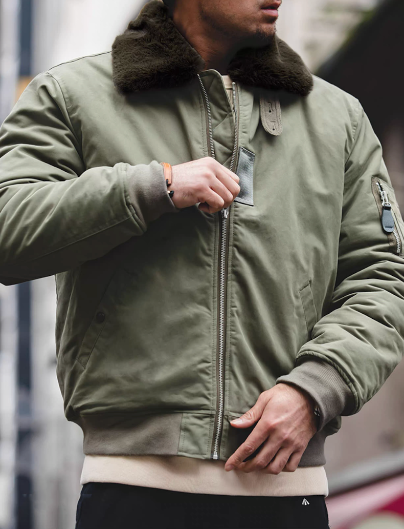 Man zipping up green B-15 bomber jacket showing military style
