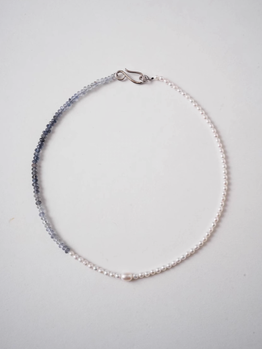 Flat lay of harmony pearl and gem necklace showing gradient transition from freshwater pearls to blue gray natural stone beads with silver clasp