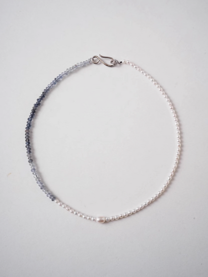 Flat lay of harmony pearl and gem necklace showing gradient transition from freshwater pearls to blue gray natural stone beads with silver clasp