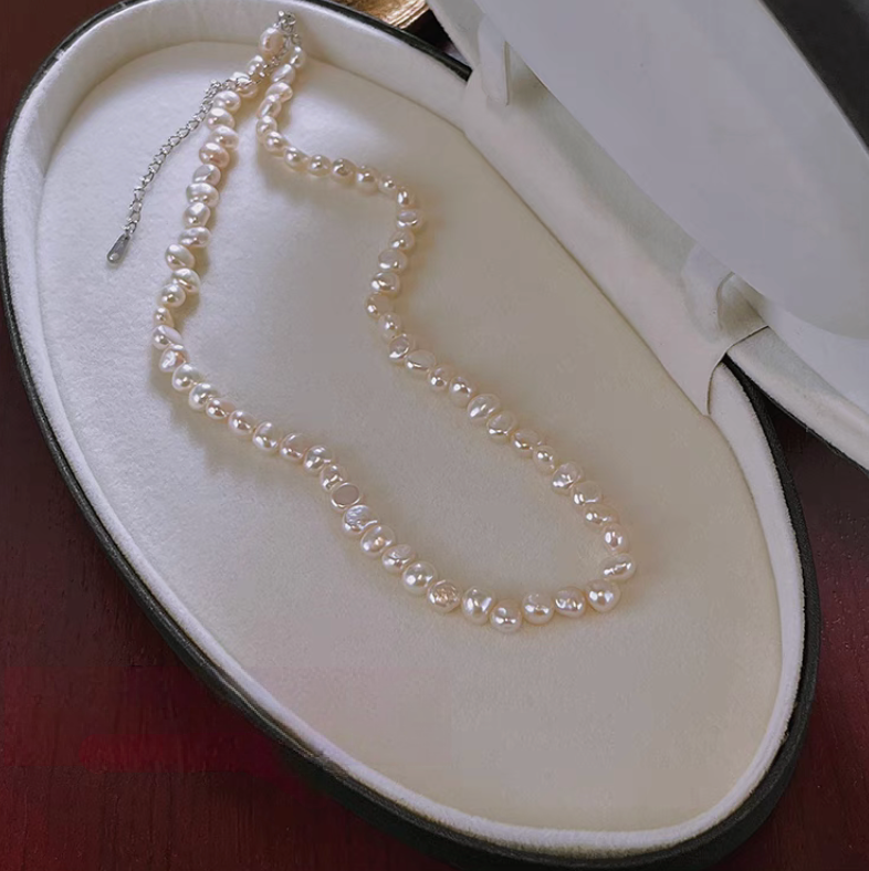 Baroque pearl necklace with silver chain extension detail displayed in jewelry box highlighting irregular freshwater pearls and adjustable clasp