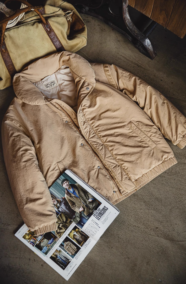 Beige Vintage Cotton-Padded Coat flat lay beside magazine and travel bag