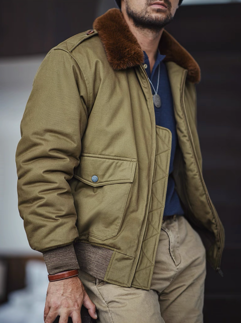 Man wearing olive B-10 flight jacket outdoors, showing brown faux-fur collar and rugged texture.