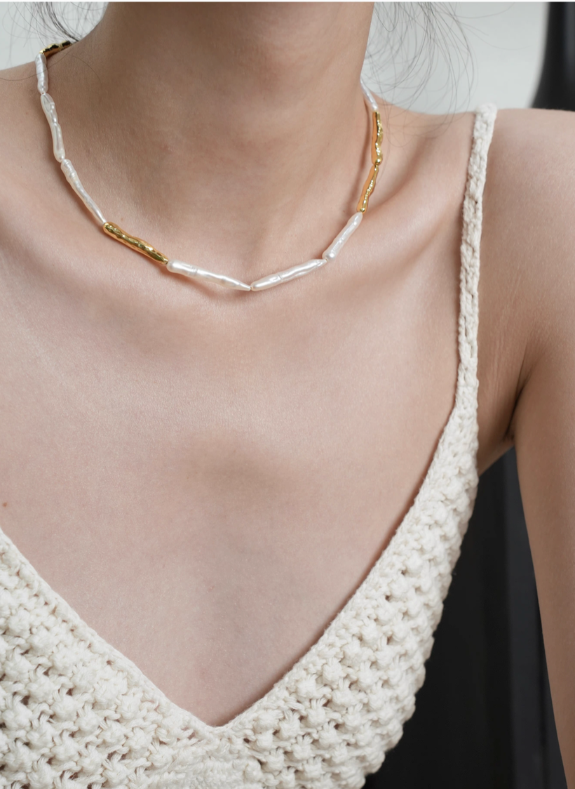 Model wearing baroque pearl gold accent choker necklace alone showing elongated pearls and gold accent centerpiece