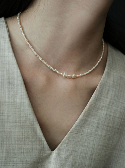 Angled view of baroque pearl and stone necklace on model showing natural freshwater pearls and soft neutral beaded texture
