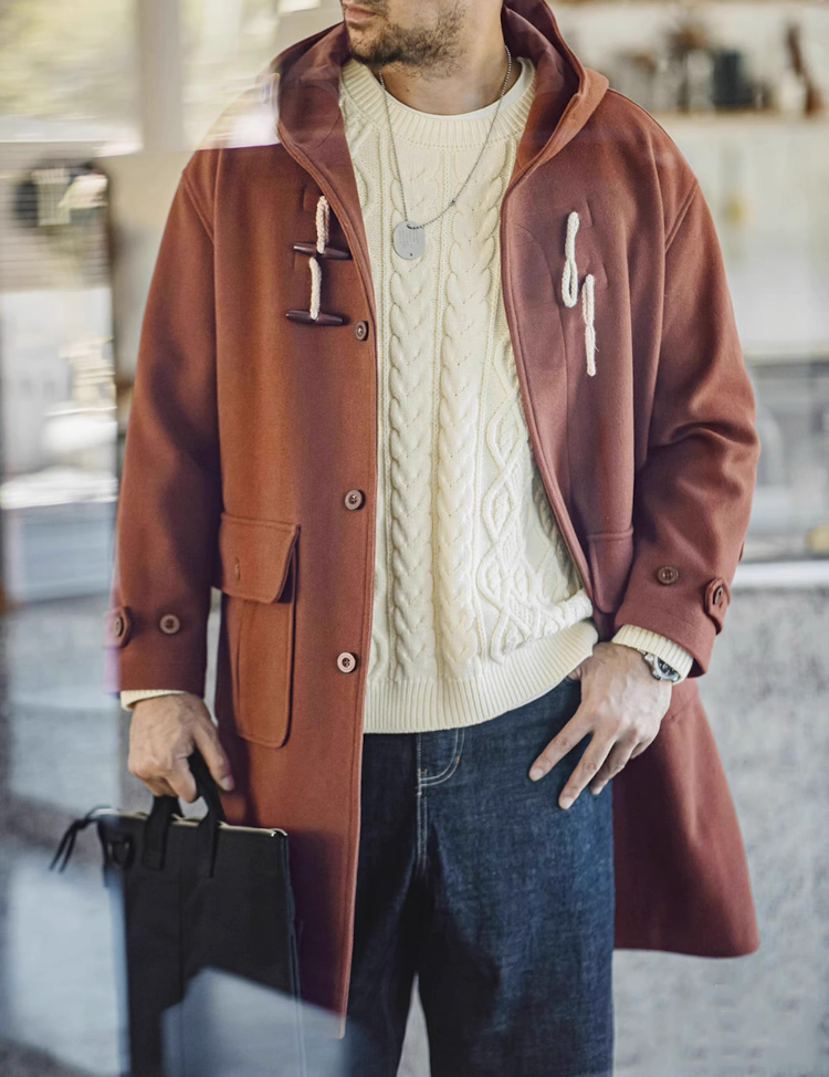 Man wearing chestnut brown toggle coat over cream sweater indoors