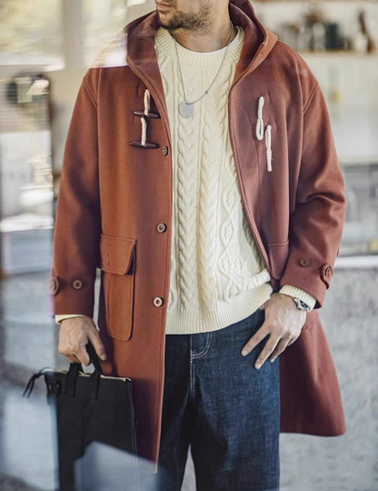 Man wearing chestnut brown toggle coat over cream sweater indoors