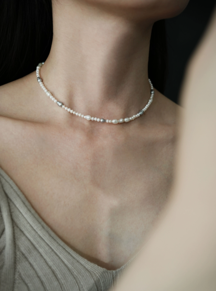 Angled view of elegant baroque pearl choker on model highlighting irregular freshwater pearls and delicate spaced bead design