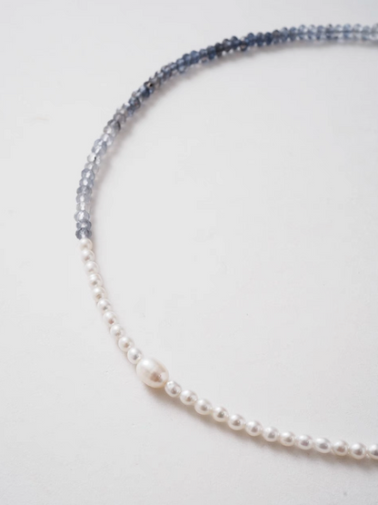 Close-up detail of harmony pearl and gem necklace highlighting transition between freshwater pearls and blue gray natural stone beads with central pearl