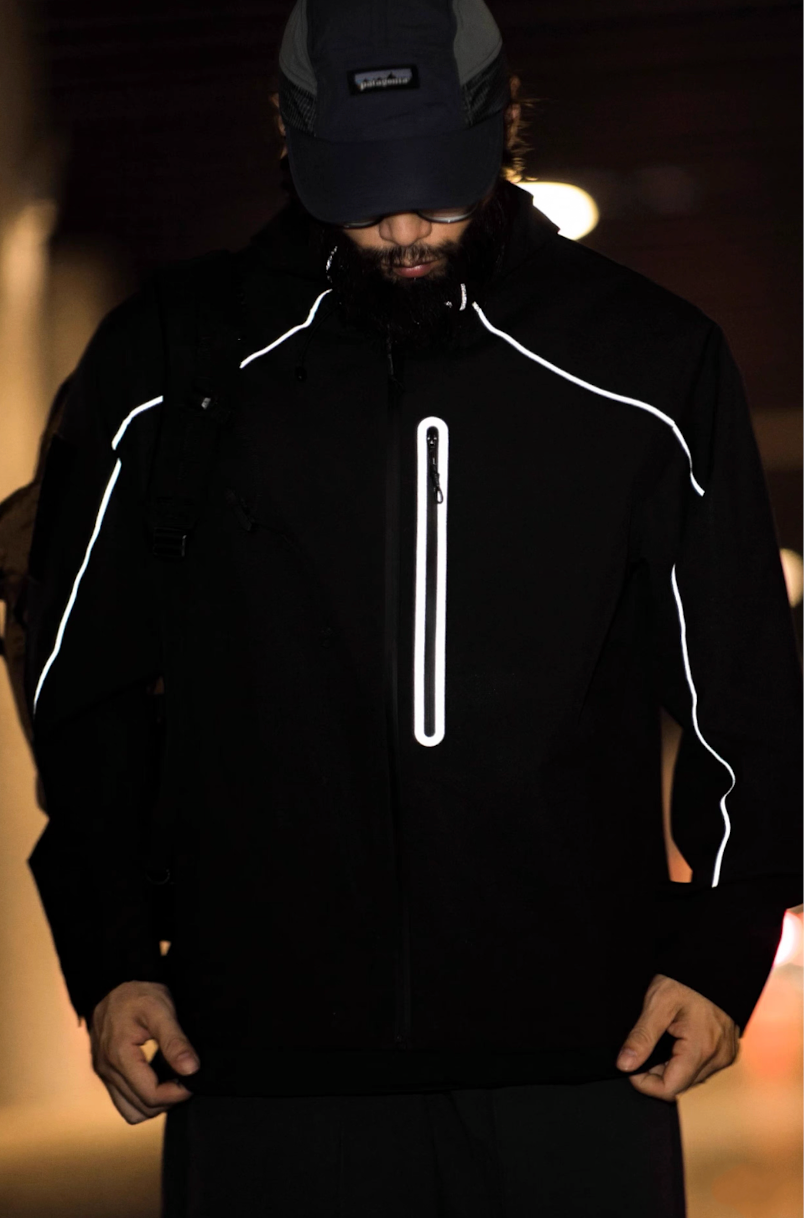 Model wearing black LIGHTSABER tech jacket in a dark urban tunnel