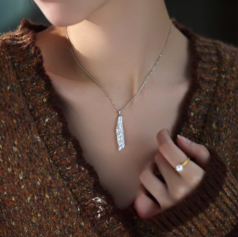 Model wearing organic baroque pearl drop necklace in silver featuring long irregular freshwater pearl pendant on fine chain