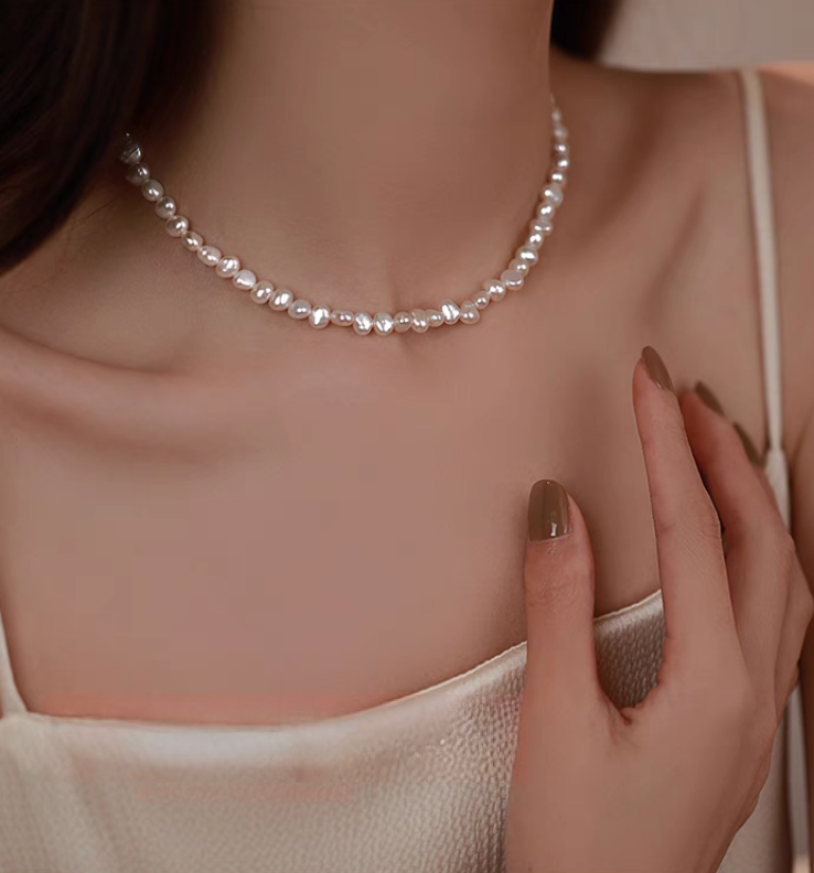 Model wearing timeless baroque pearl and silver necklace close-up showing unique irregular freshwater pearls along neckline