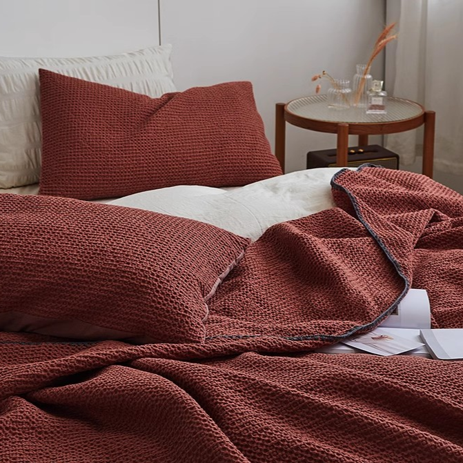 Detailed view of burgundy honeycomb waffle cotton throw blanket showing breathable woven texture and soft cotton fibers.