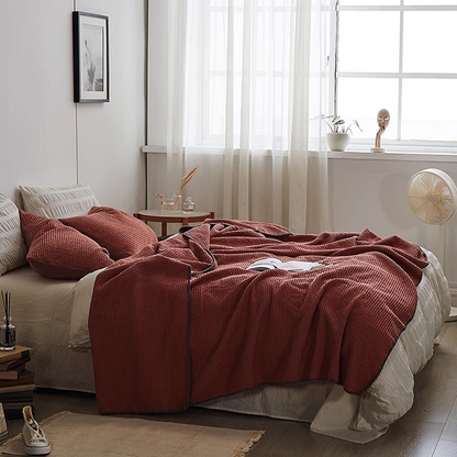 Burgundy 3D honeycomb waffle cotton throw blanket styled across a modern bedroom bed with natural lighting and minimal décor.