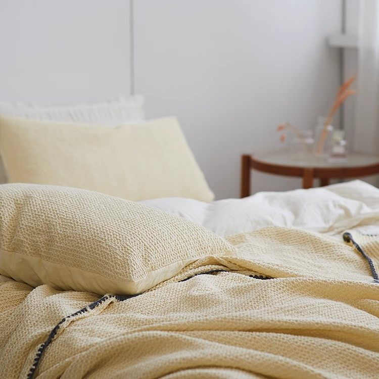 Close-up view of light yellow 3D honeycomb waffle cotton throw blanket highlighting breathable textured cotton fabric.