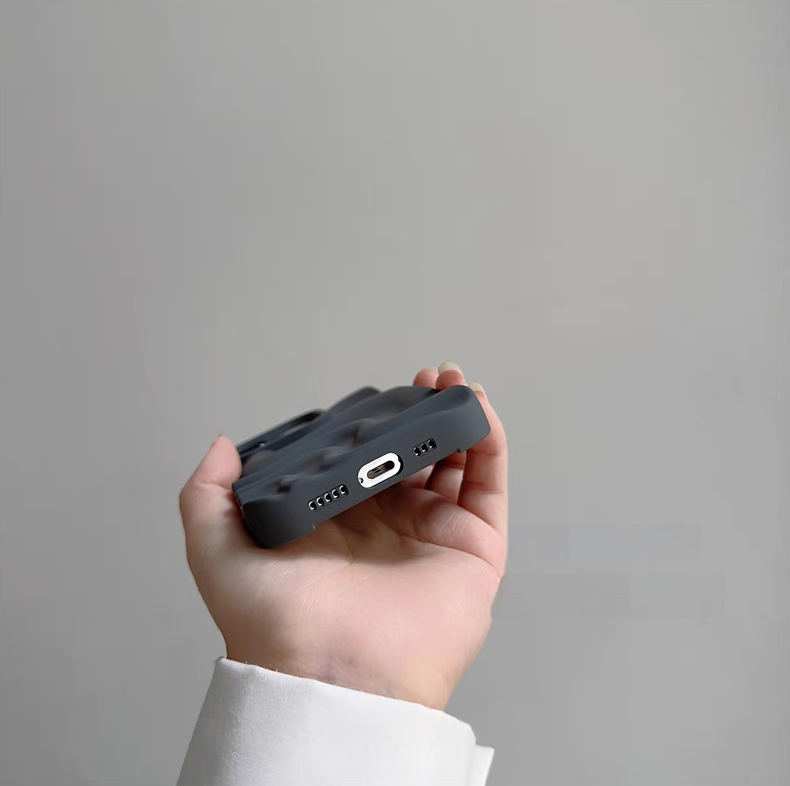 Gray matte silicone phone case showing bottom cutouts for charging port and speakers with 3D wave texture