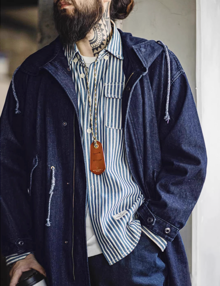 Side view of man styling M-51 denim fishtail parka in deep indigo tone