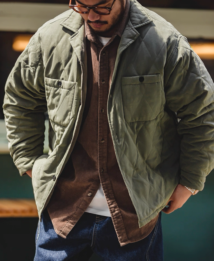 Army green quilted jacket layered over brown corduroy shirt