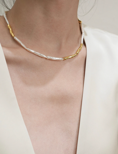 Close-up of baroque pearl gold accent choker necklace on model with blazer highlighting gold accent and pearl arrangement