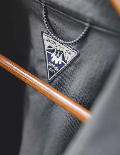 Close-up of collar logo tag inside men’s dark charcoal overshirt jacket.